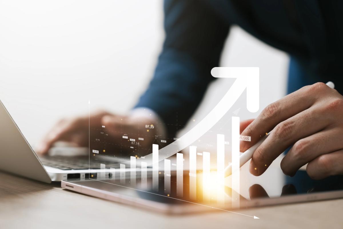 Professional working on a laptop, with a graphical overlay of increasing bar graphs and an upward arrow, symbolizing business growth and partnership opportunities with a luxury car rental company in Switzerland.