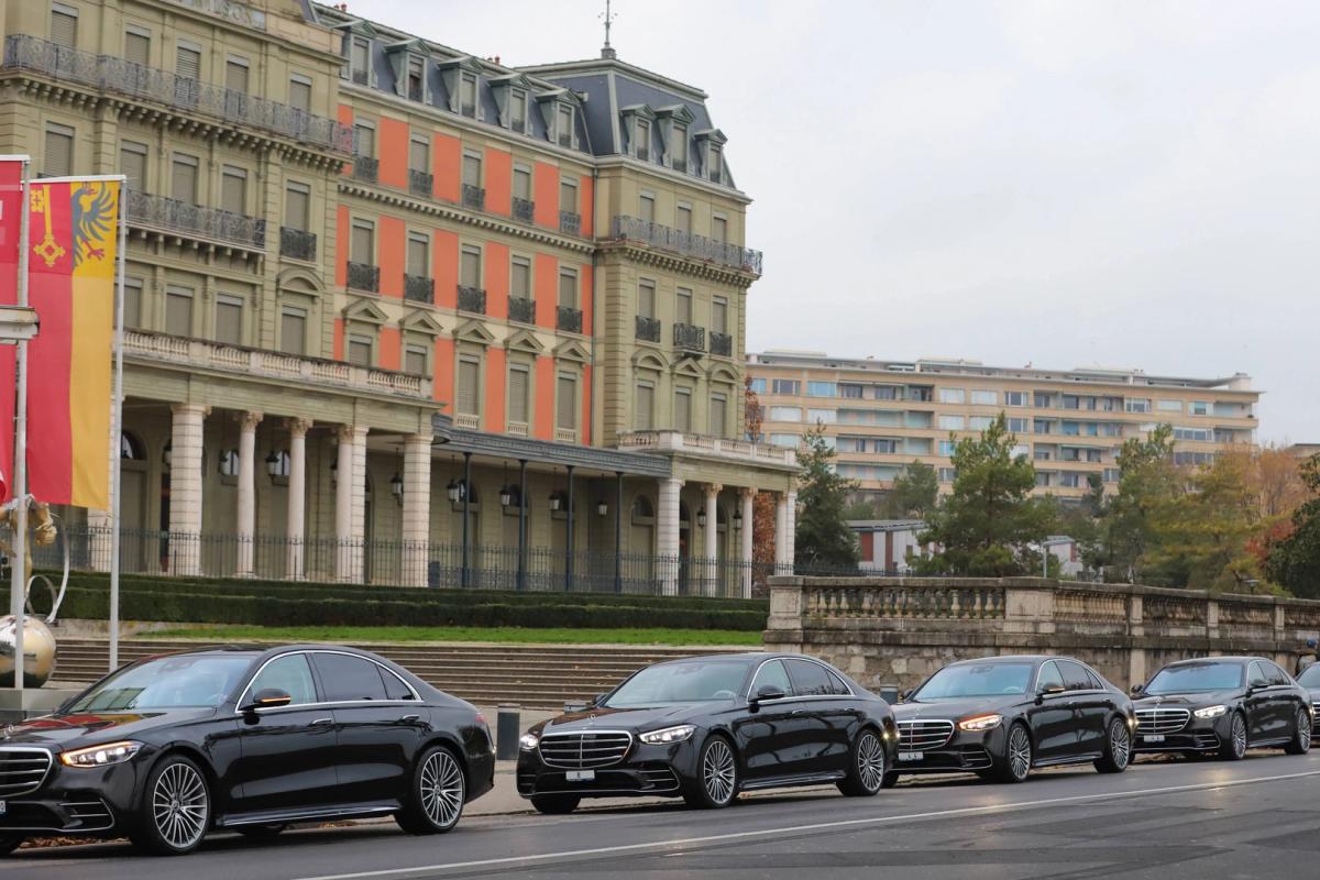 Row of luxury cars, possibly for rental, parked in front of an elegant building, showcasing their polished black exteriors and modern design. The architecture and the cars together reflect an aura of affluence and sophistication, making it an ideal choice for luxury car rentals in Switzerland.